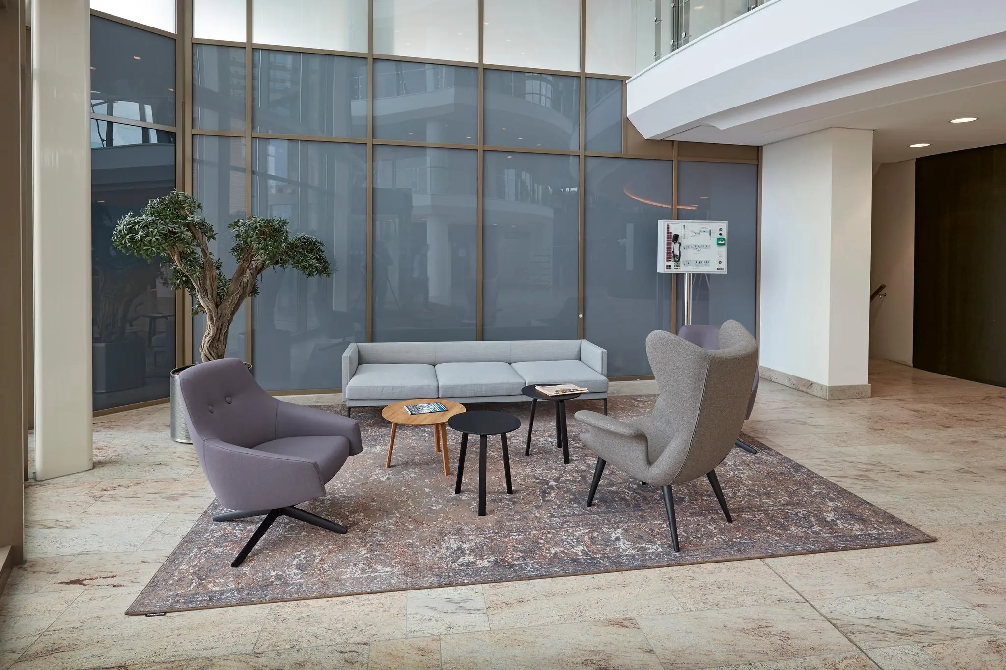 Moderne wachtruimte aan de Fascinatio Boulevard met designmeubilair, grote kamerplant en een glazen wand.